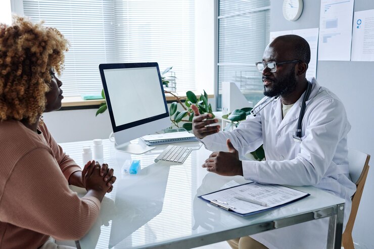african-male-doctor-white-coat-sitting-table